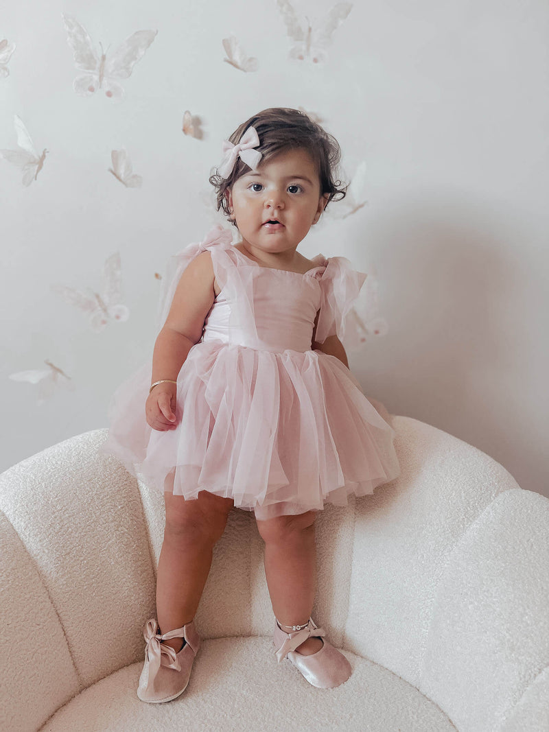 Harper tulle baby flower girl romper in dusty pink, is worn by a toddler.