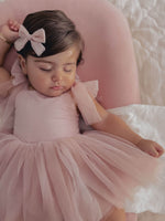 Harper dusty pink baby romper and matching tulle bow hair clip are worn by a sleeping baby girl.