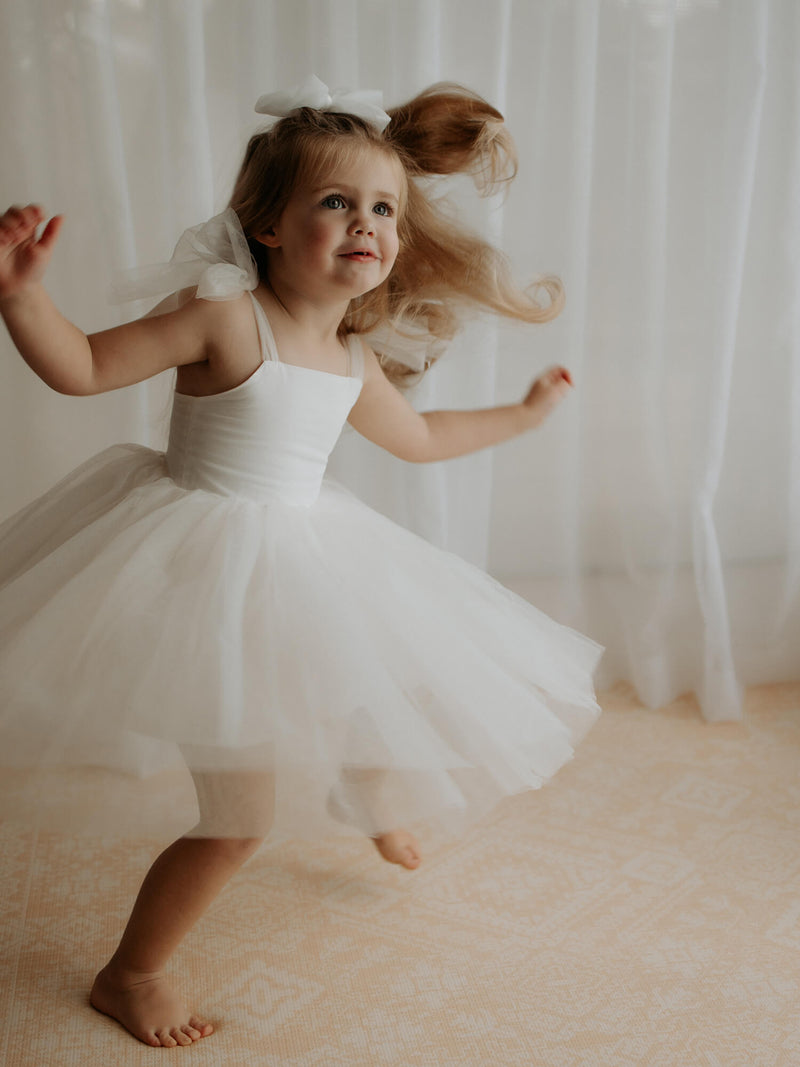 A girl dances and twirls in our Harper tea length flower girl dress.