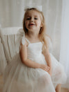 Harper cream flower girl dress is worn by a young girl.