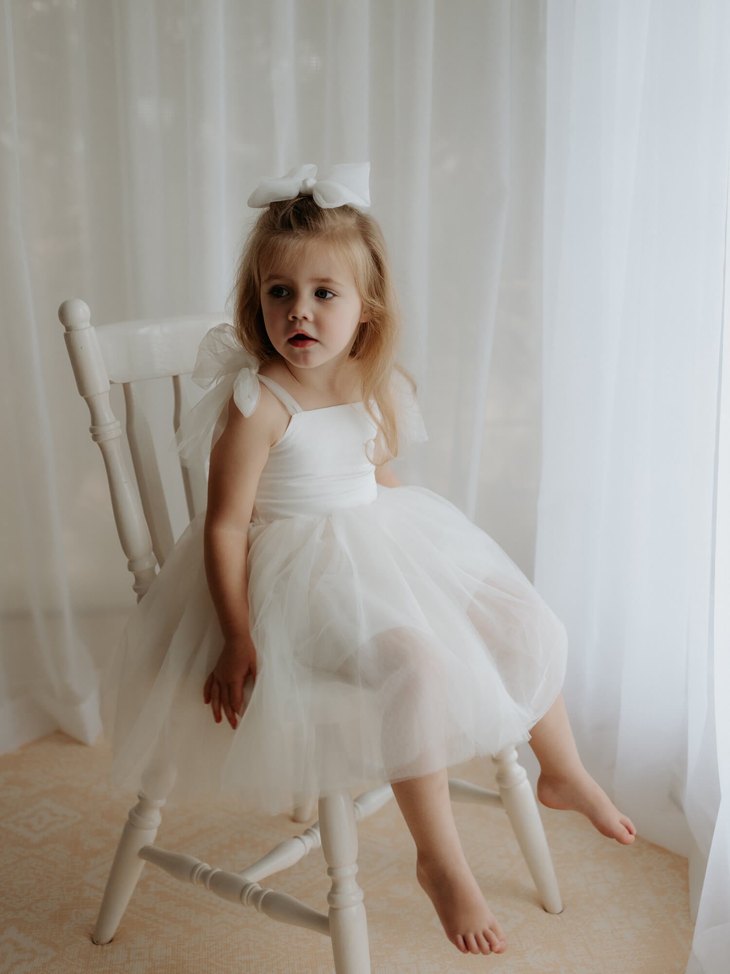 Harper cream tulle tie flower girl dress is worn by a flower girl.