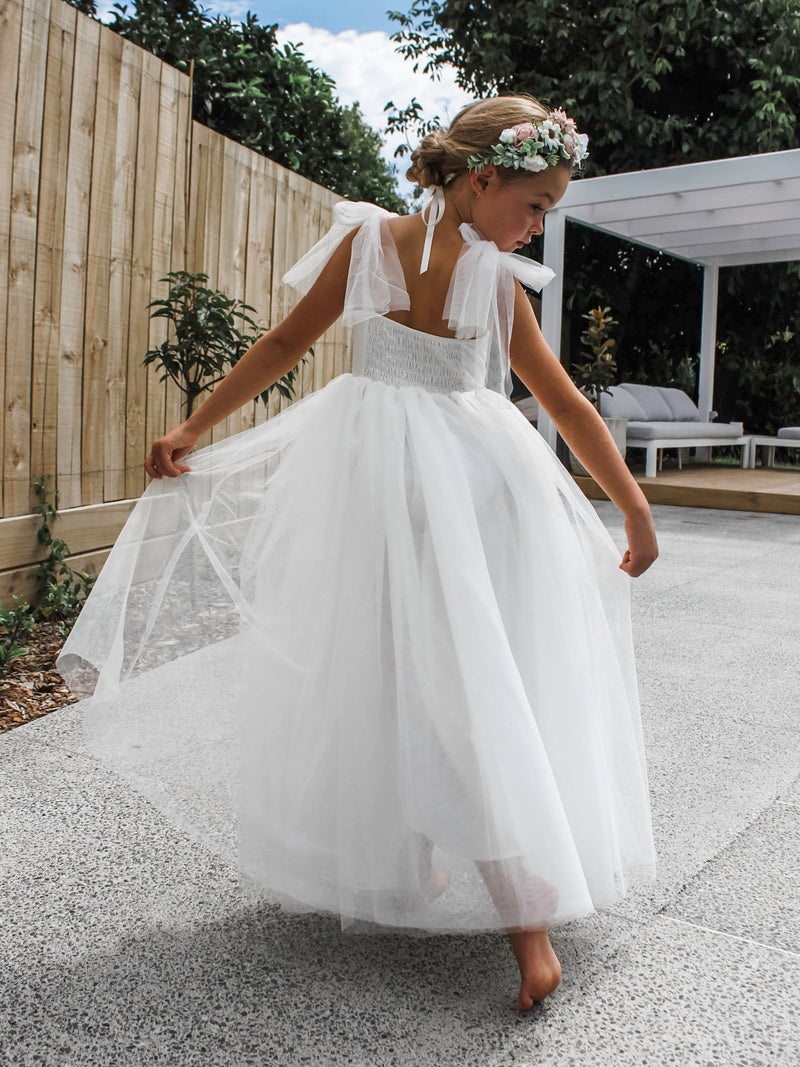 Tulle flower girl dress being worn by a young girl. Beautiful ivory tulle dress with feature tulle tie straps.