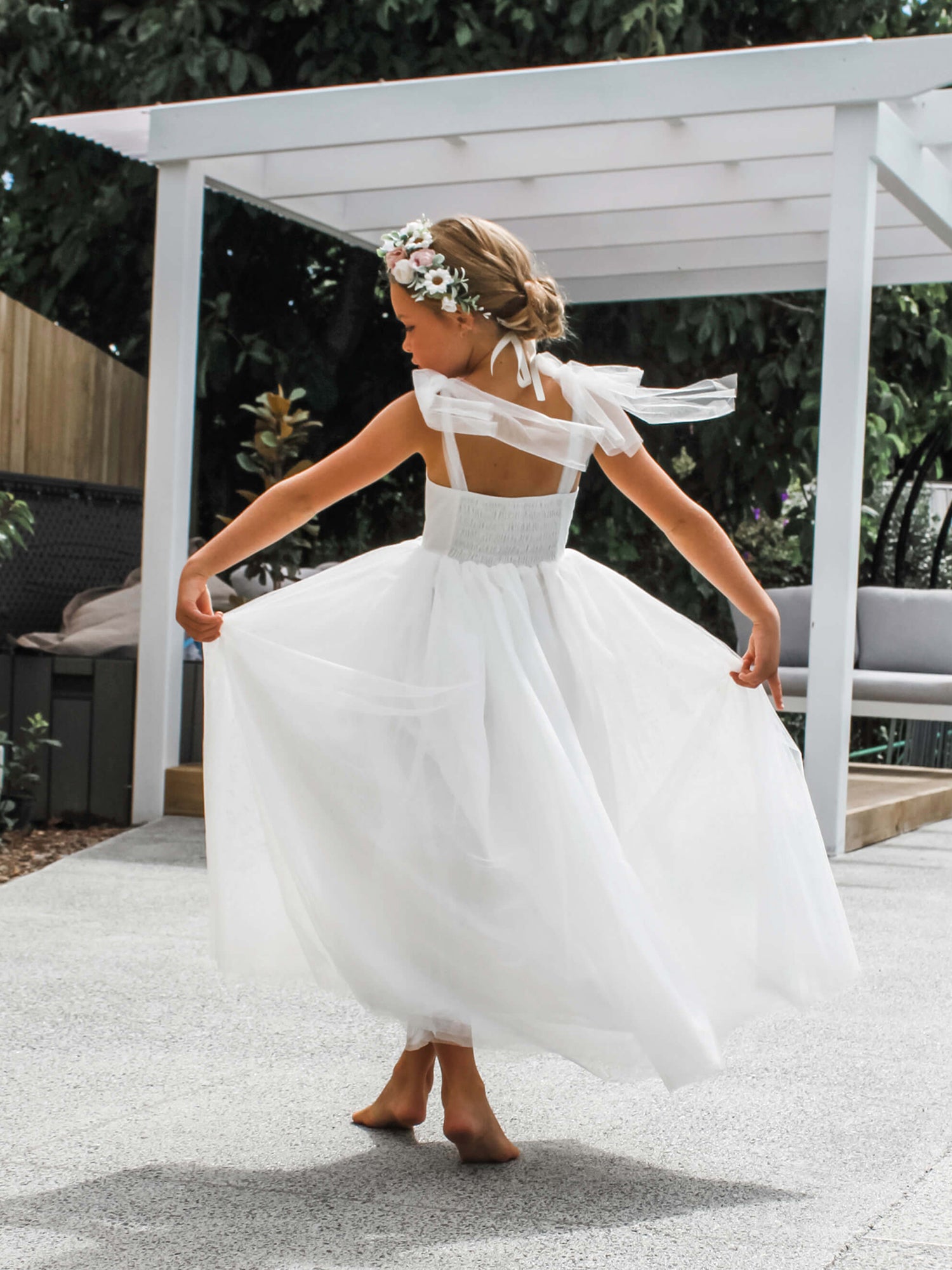Harper flower girl dress worn by a young girl. Soft tulle skirt and straps with a shirred bodice. Worn with our Daisy flower crown.