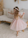 A young girl dances wearing our Harper flower girl dress in dusty pink and Elsie girls flower crown.