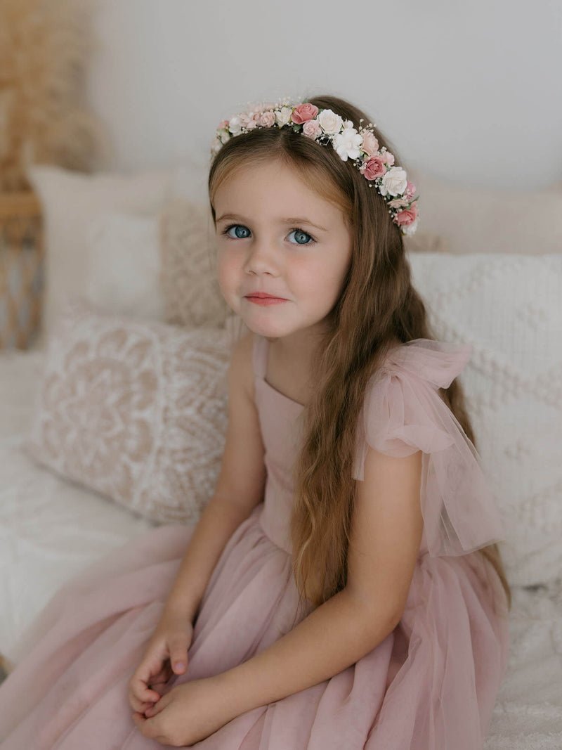 Harper dusty pink flower girl dress is worn by a girl, showing the soft tulle tie straps and soft tulle skirt. She also wears an ivory and pink flower crown.