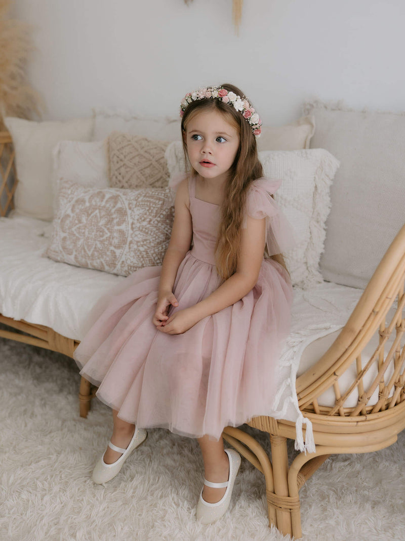 Harper dusty pink tea length flower girl dress is worn by a young girl.