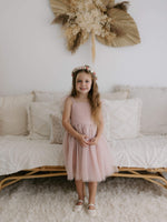 A little girl smiles wearing our Harper tea length flower girl dress in pink, along with our Elsie girls flower crown.