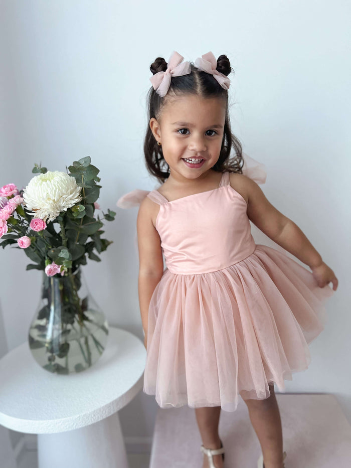 Isla champagne baby flower girl dress is worn by a toddler. She also wears our tulle champagne pigtail bows in her hair.