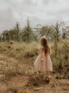 A young girl walks outside wearing our champagne tulle Isla flower girl dress.