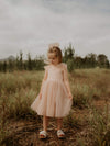 Isla champagne flower girl dress being worn with a matching tulle bow hair clip.