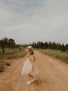 Isla champagne flower girl dress is worn by a young girl, dancing outside.
