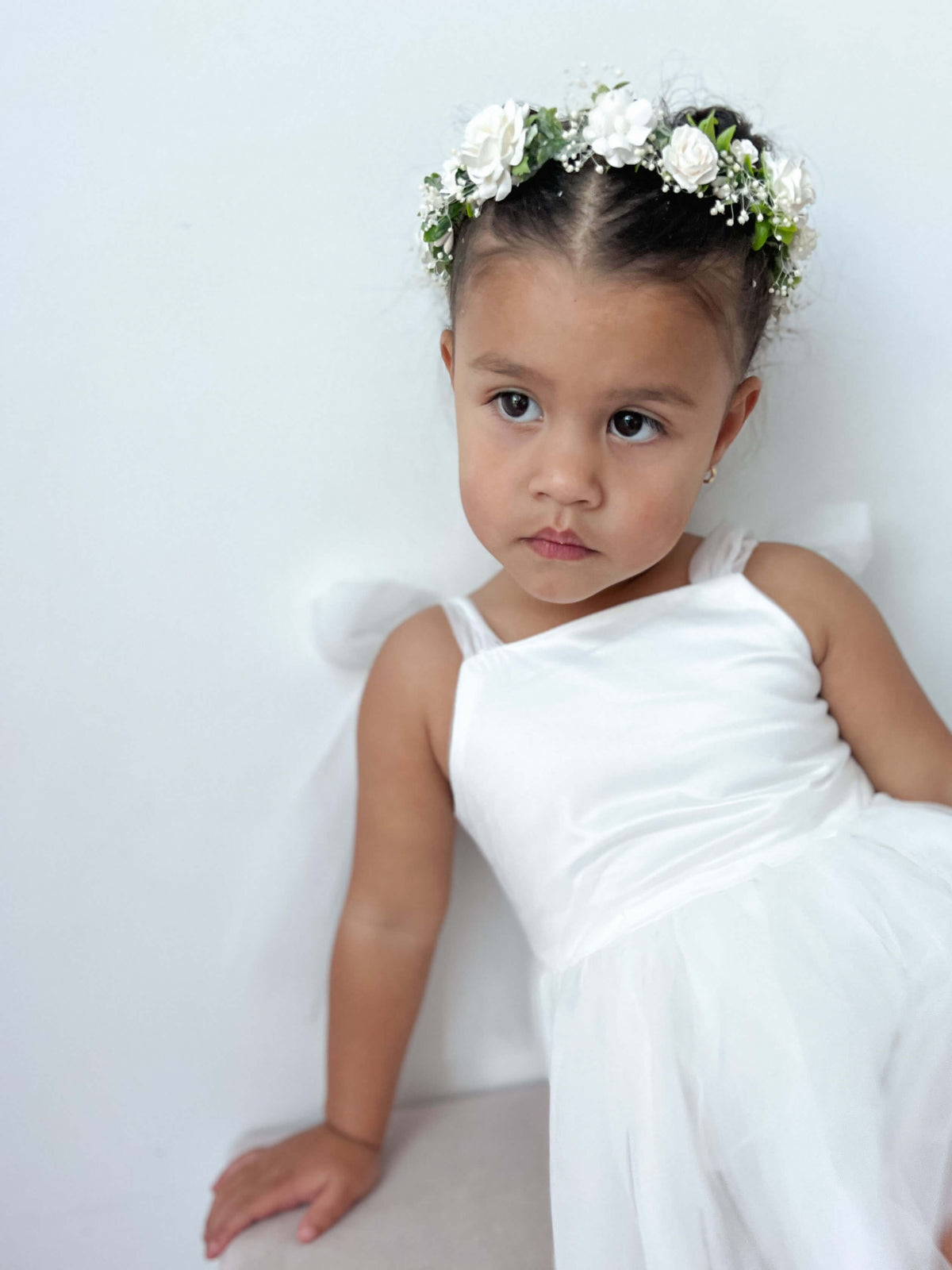 A toddler wears our ivory Isla flower girl romper and Elsie girls flower crown.