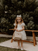 Kenzi flower girl dress is worn by a young girl holding a basket.