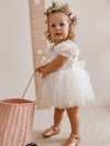 Young toddler flower girl wears our Layla baby flower girl romper dress, and our Daisy flower crown. She pushes a wicker basket.