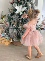 A young girl wears our Layla dusty pink baby flower girl dress, with tulle puff sleeves and a tulle bow at the back.