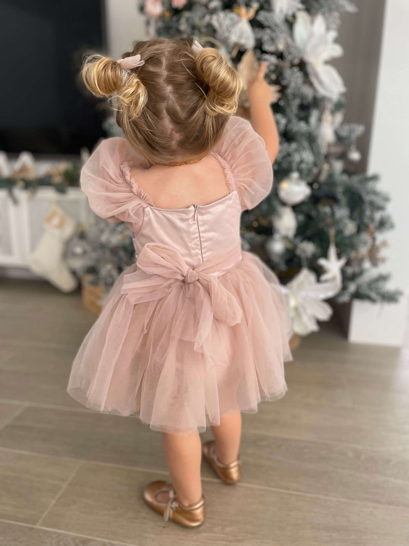 Layla baby flower girl romper in dusty pink is shown from the back on a toddler.