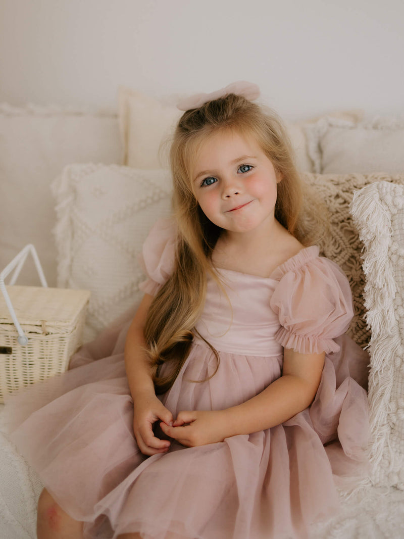 Tulle puff sleeve flower girl dress is worn by a young girl.