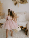 Layla flower girl dress in dusty pink is worn by a young girl who is twirling.