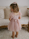 The back of our Layla flower girl dress in dusty pink. Showing the zip back closure and tulle waist sash, tied in a bow at the back.