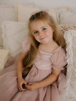 Layla dusty pink flower girl dress is worn by a young girl, showing the satin bodice, tulle puff sleeves and tulle skirt.