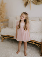 Layla puff sleeve flower girl dress in dusty pink is worn by a young girl.