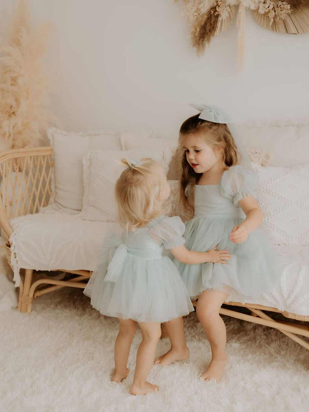 Matching Layla flower girl dresses in dusty blue are worn by two sisters.