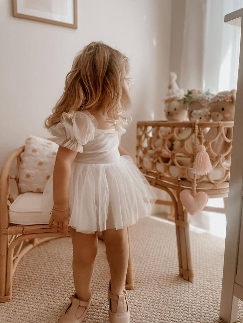 A toddler wears our Layla ivory tulle flower girl romper.