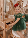 Clara puff sleeve Christmas romper is worn by a toddler. She also wears our Clara girls Christmas floral headband.