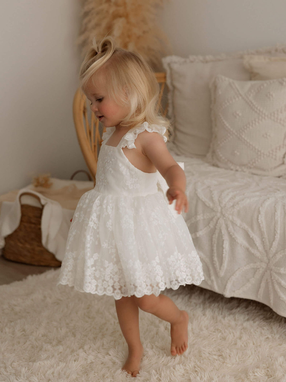 A little girl twirls while wearing our ivory lace Loulou flower girl romper.