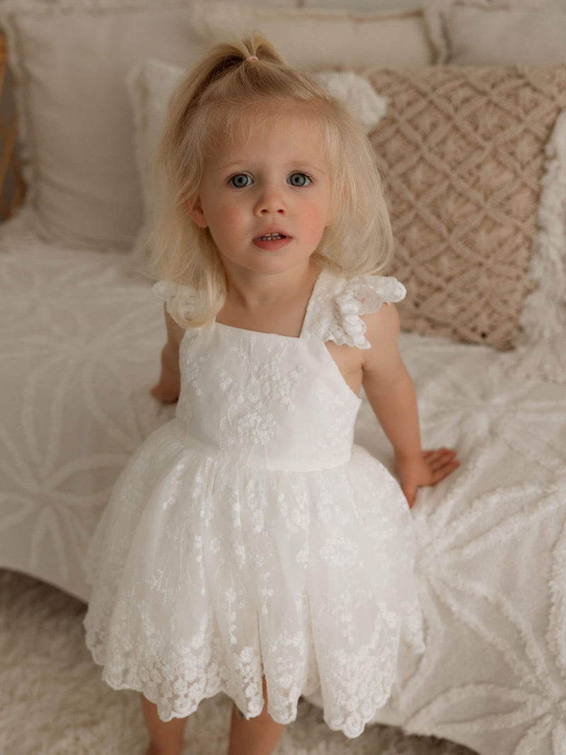 A little girl wears our ivory lace Loulou flower girl romper.