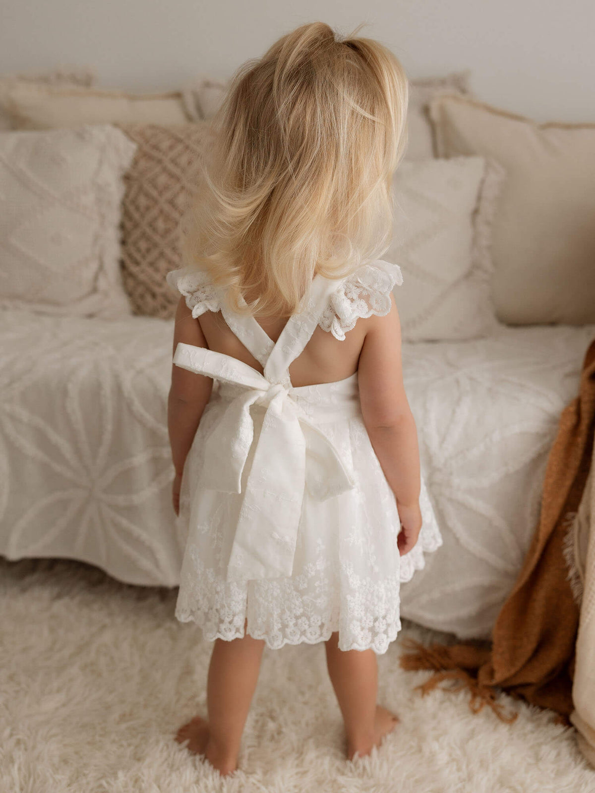 The back of our lace flower girl Loulou romper with bow tied at the back.