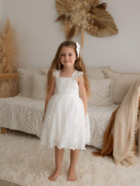 Loulou lace flower girl dress is worn by a young girl. She also wears our small satin bow hair clip in her hair.