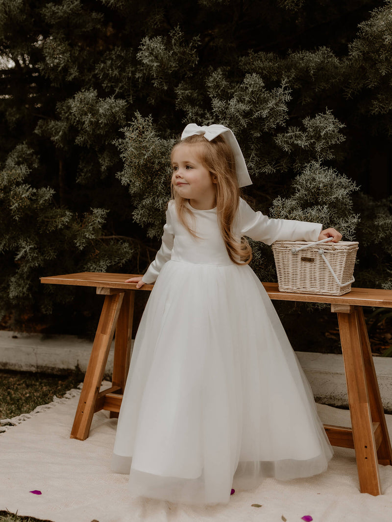Lucy flower girl dress for winter is worn by a young girl. She also wears a satin bow clip in her hair.