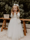 Lucy winter flower girl dress is worn with our Chloe cardigan over the top. She also wears a satin bow clip hair accessory.