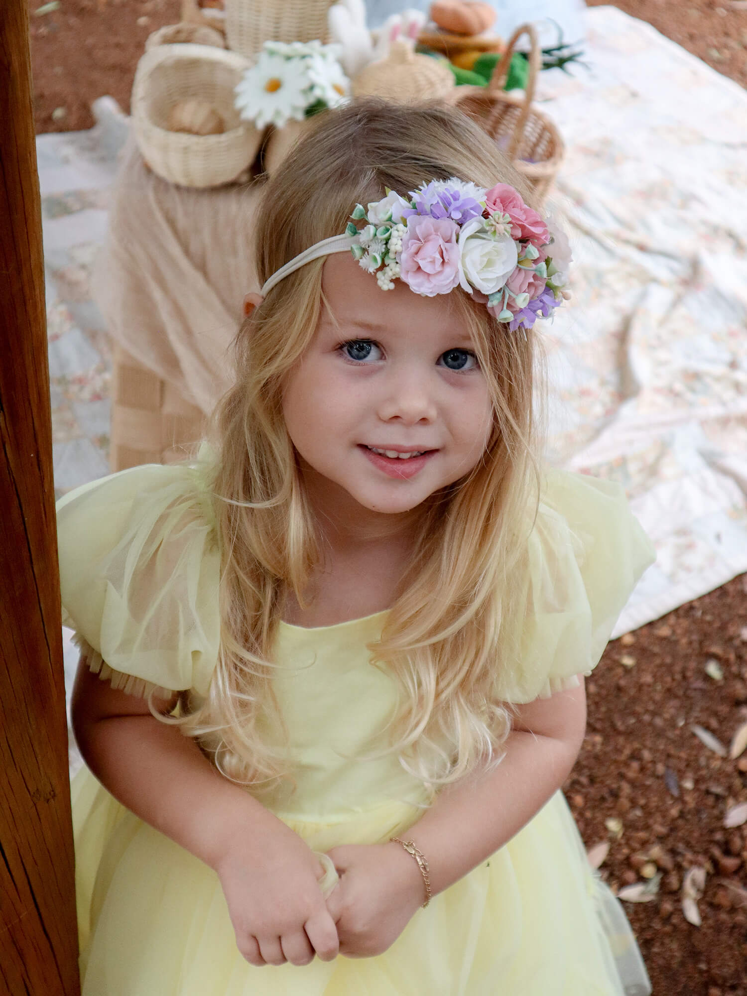 Luna floral headband with pink and purple flowers is worn by a young girl in a yellow tulle dress.