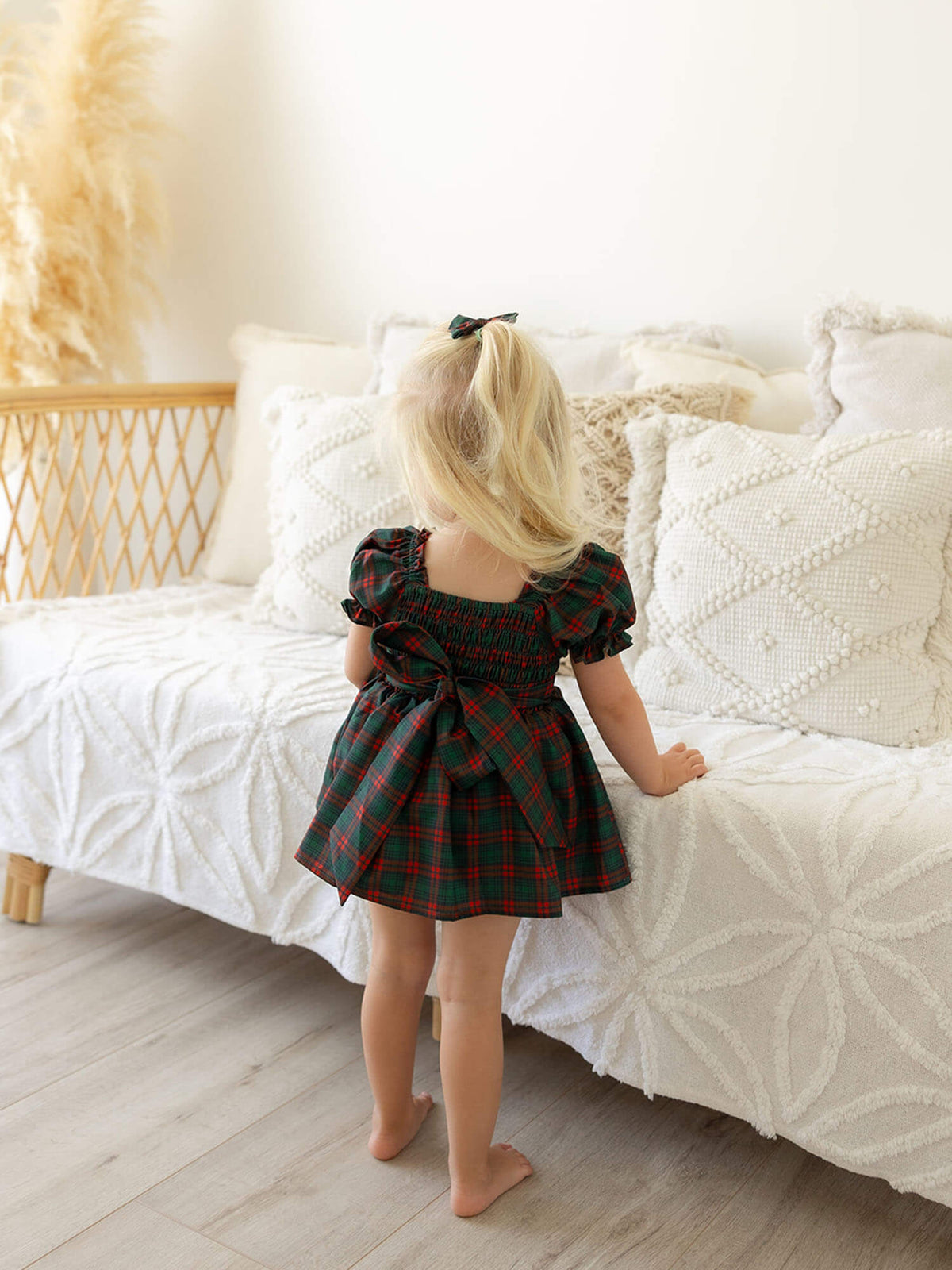 The back of our Mila tartan baby Christmas romper, worn by a toddler.