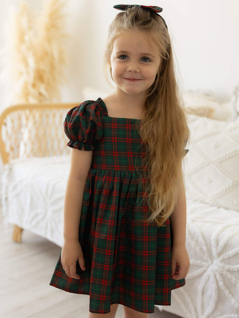 A young girl wears our tartan Christmas dress, Mila dress in Christmas plaid.