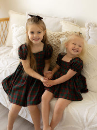 Sisters wearing matching Mila Christmas dress in tartan and Mila tartan Christmas romper.