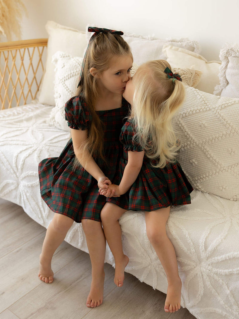 Sisters wearing our matching tartan girls Christmas dresses and matching tartan hair bows.