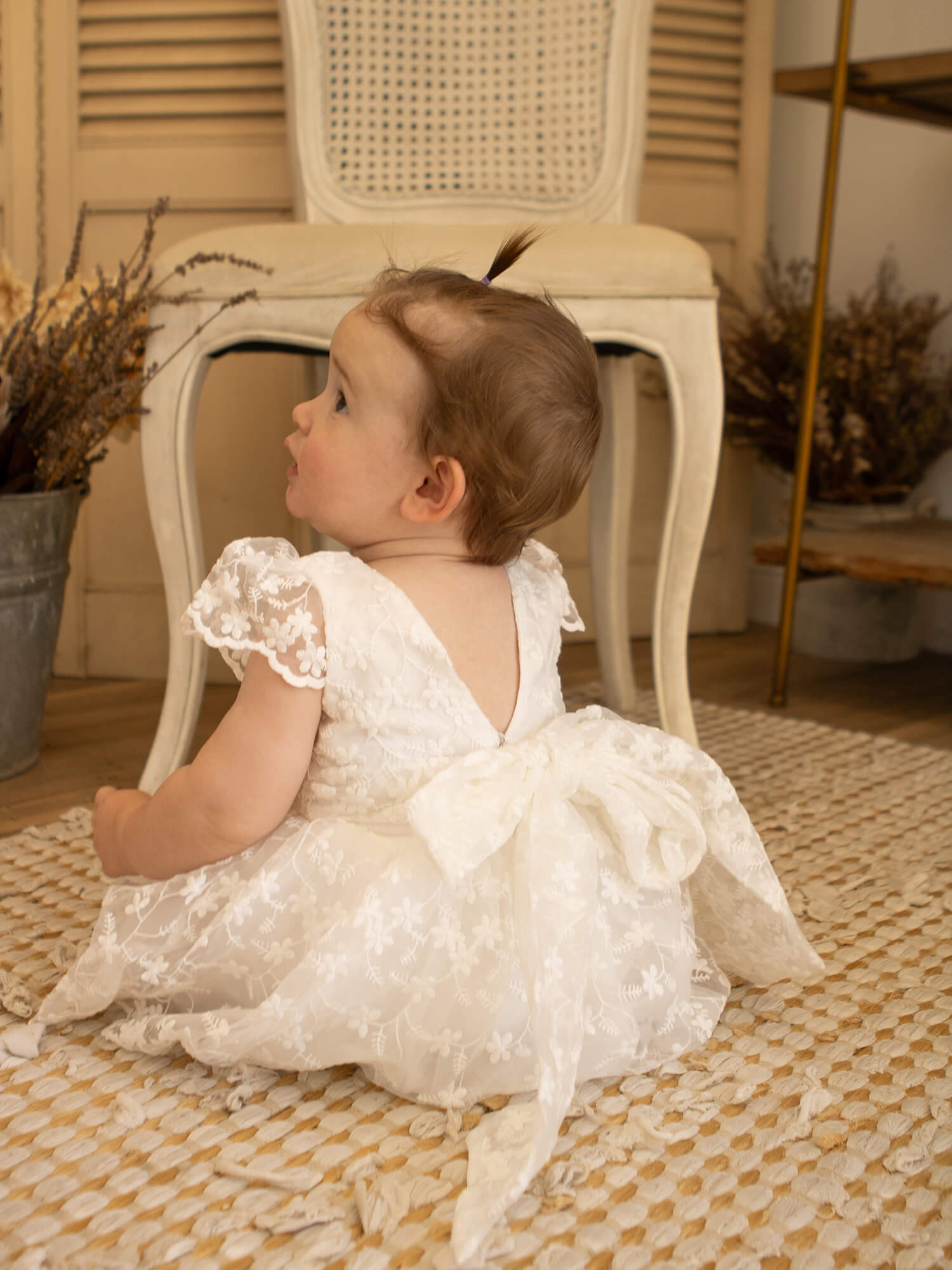 Pippa lace baby dress shown from the back, showing the oversized lace bow at the back.