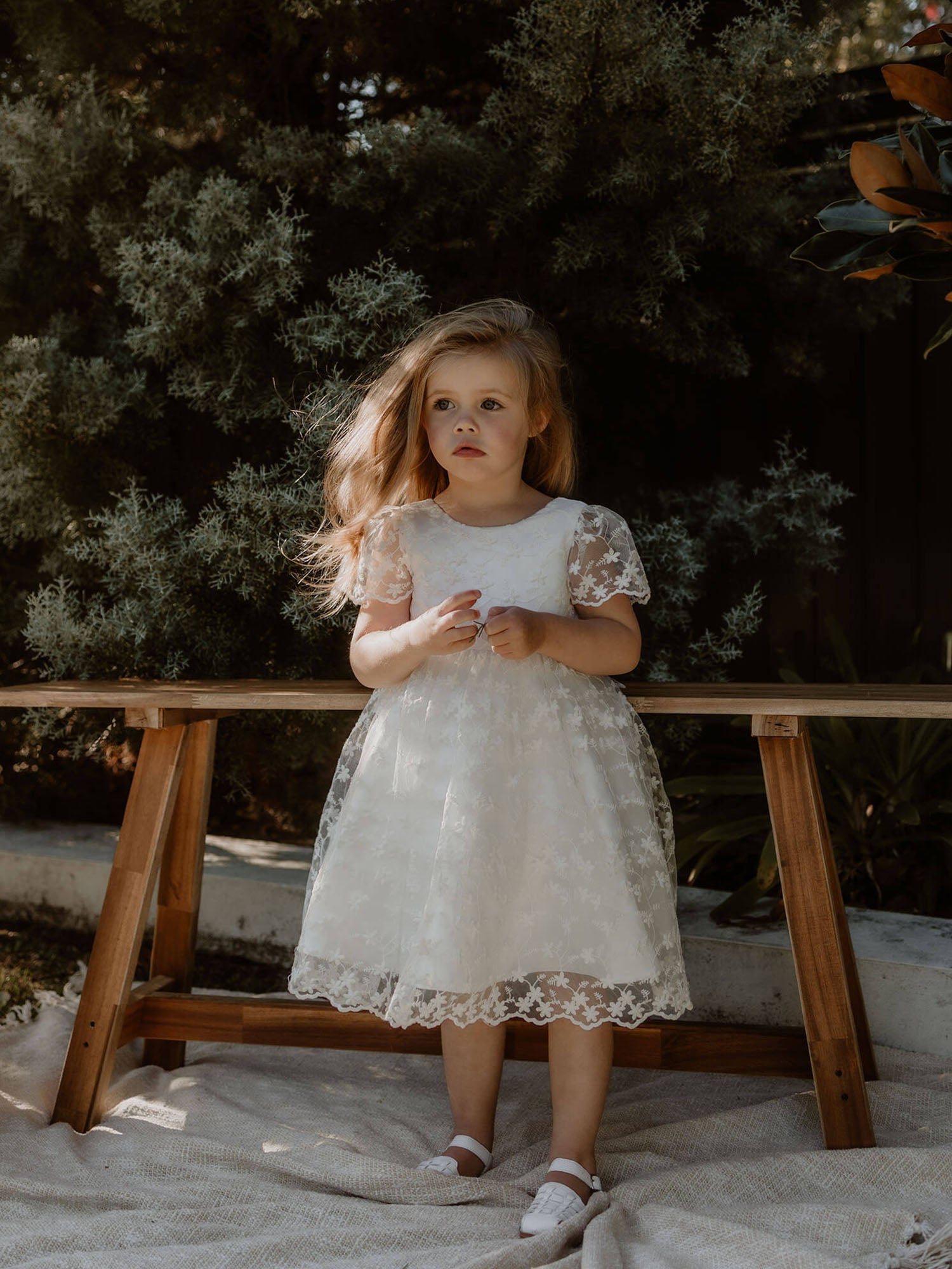 Pippa floral flower girl dress is worn by a young girl, showing the dainty floral lace.