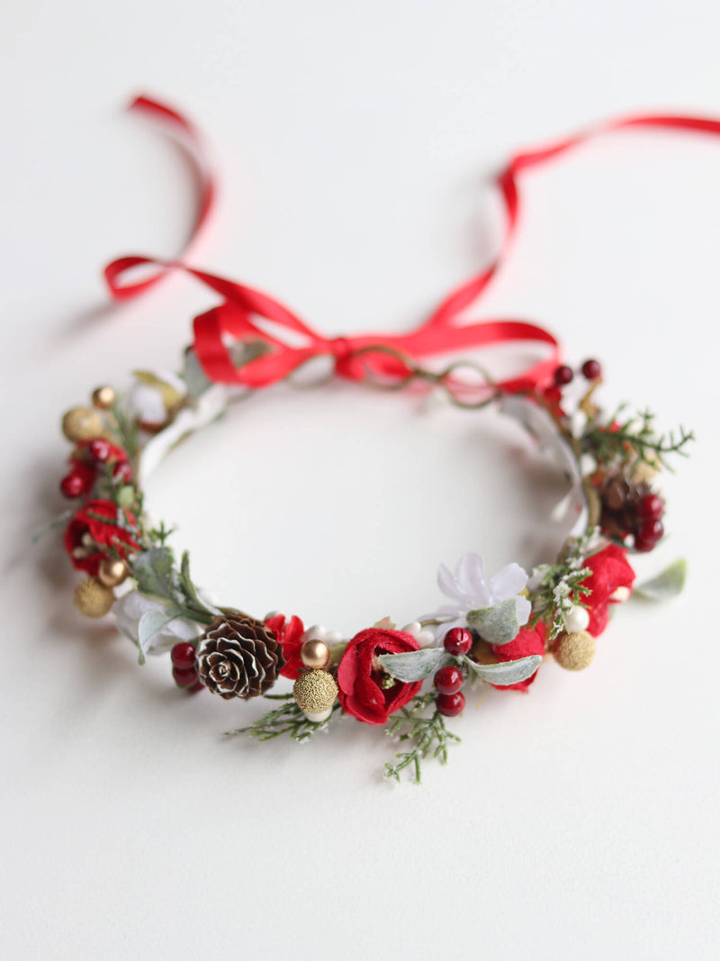 Winter flower crown with red ribbon tie, red florals and pinecone accents.