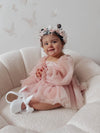 Wren flower girl romper in dusty pink is worn by a toddler, along with a matching flower crown.