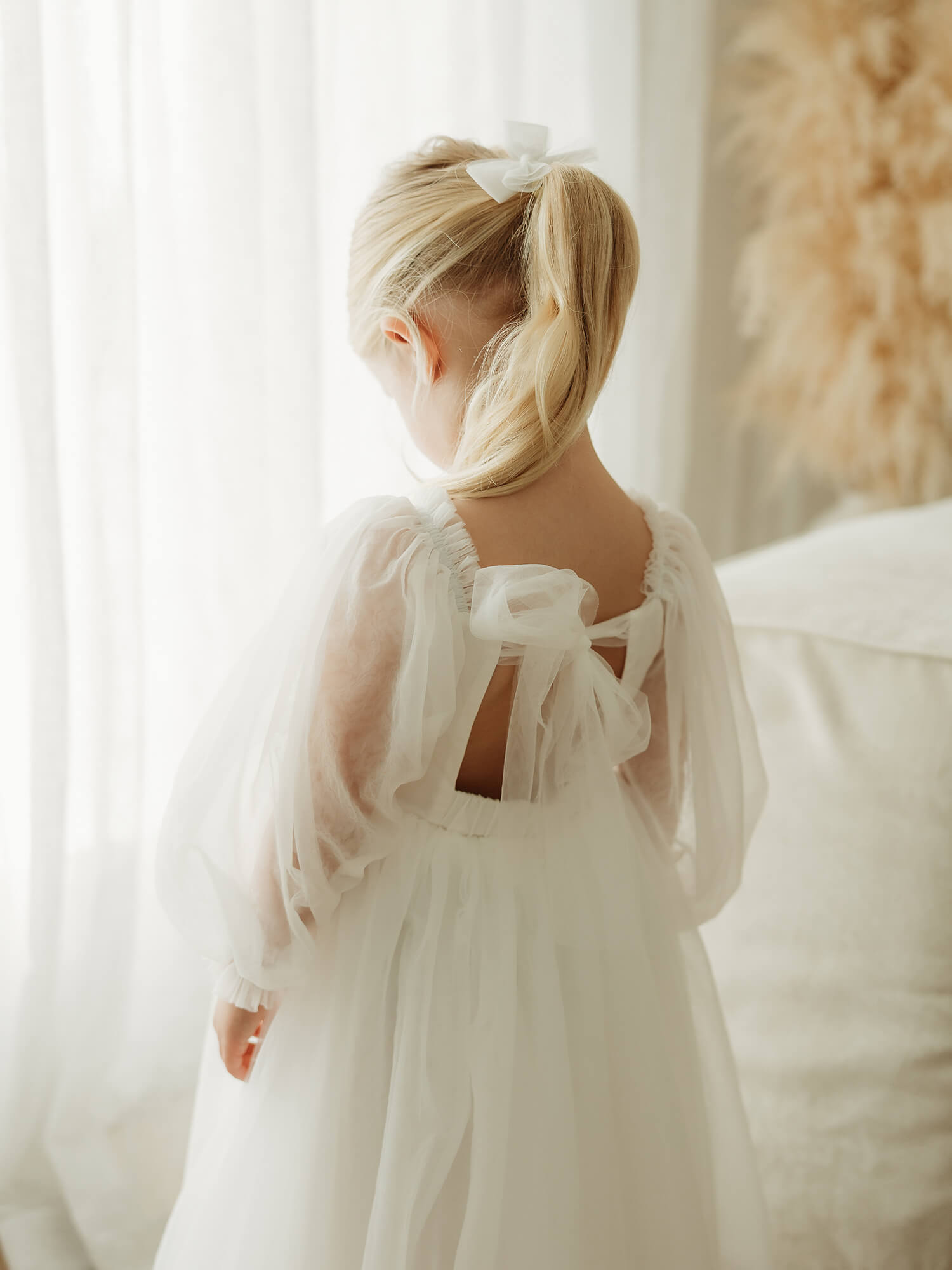 The back of our ivory Wren full length flower girl dress, showing the tulle bow back.