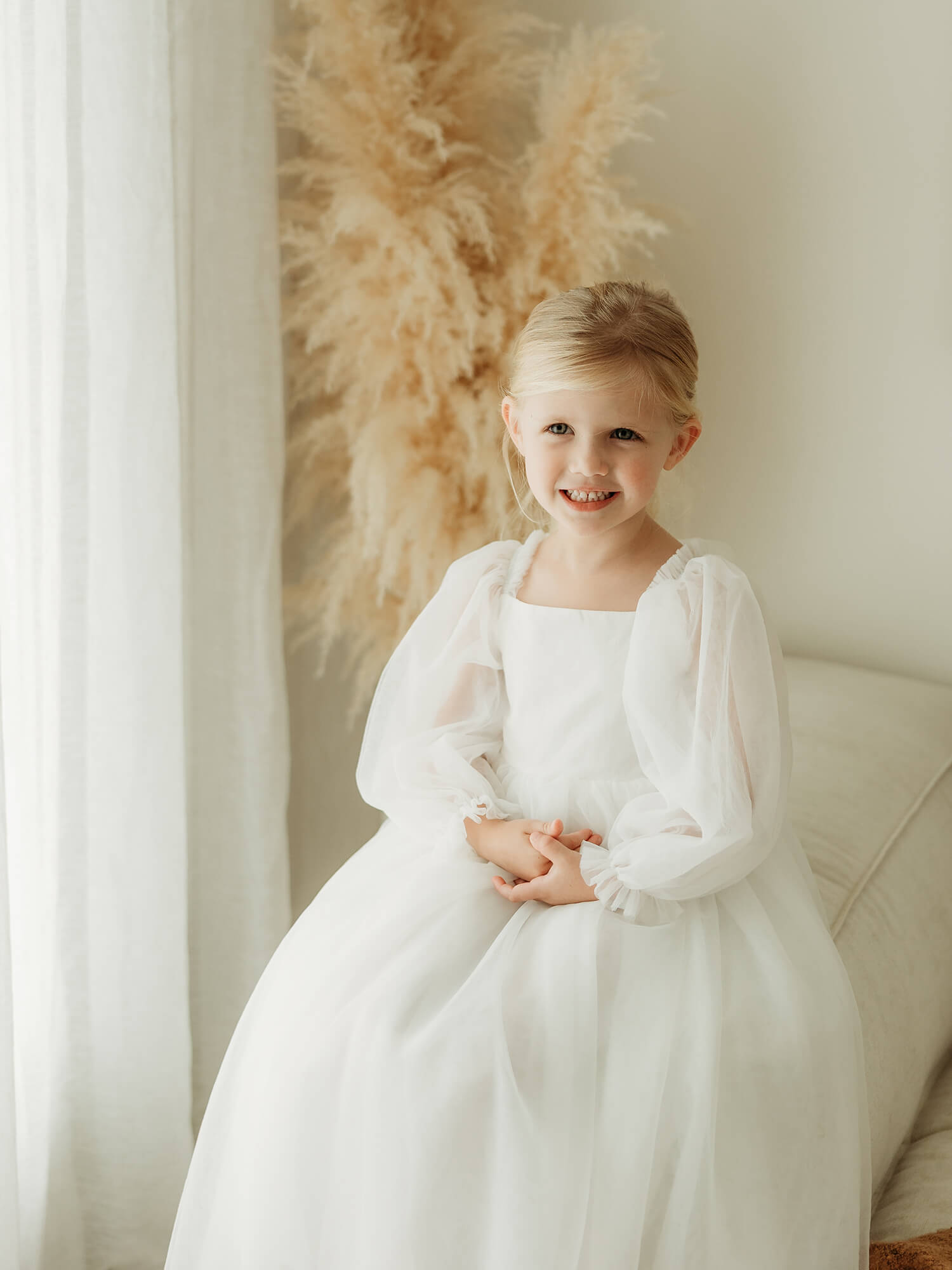 Wren full length white flower girl dress is worn by a young girl.