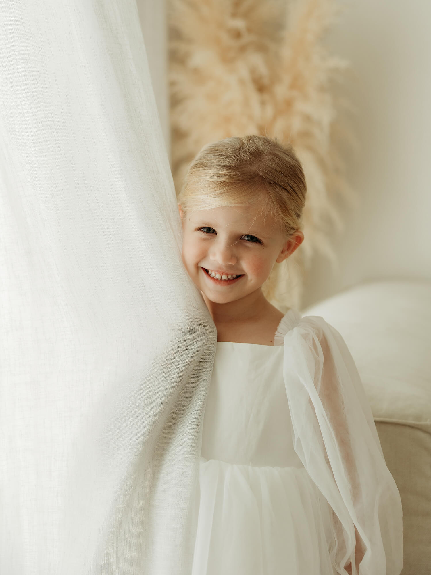 Ivory Wren flower girl dress is worn by a young girl who is smiling.