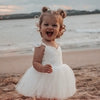 Everly lace and tulle baby romper in ivory being worn by a toddler, who is at the beach.