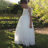 Sonnet ivory flower girl dress worn by a young girl, along with our Grace girls flower crown. She stands in a garden in the full length tulle flower girl dress.