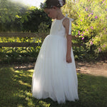 Sonnet ivory flower girl dress worn by a young girl, along with our Grace girls flower crown. She stands in a garden in the full length tulle flower girl dress.
