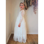 Lumi full length lace flower girl dress, being worn by a young girl. Showing the tiered lace dress.